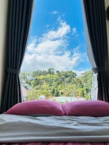 a bed with a window with a view of a mountain at Cloud River Homestay in Da Lat