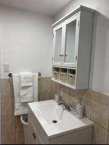 a bathroom with a sink and a white cabinet at Cozy Spacious Work Friendly Lotus with Garden View High speed free Wi Fi and Parking Adjacent to Downtown Montreal in Montreal