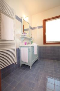 Baño de azulejos azules con lavabo y espejo en Albergo Diffuso Polcenigo C.Barnard, en Polcenigo