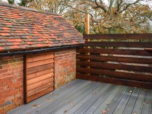 a wooden deck next to a brick fence at Kingfisher Granary in Ashburnham