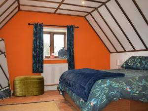 een slaapkamer met oranje muren en een bed en een raam bij Kingfisher Granary in Ashburnham