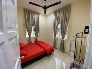 a bedroom with a red bed and two windows at BARAKAH HOMESTAY in Kota Tinggi