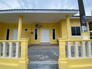 a yellow building with a white door and columns at BARAKAH HOMESTAY in Kota Tinggi