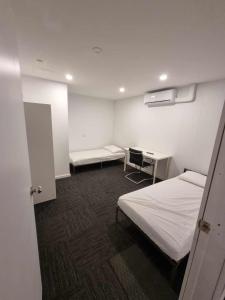 Habitación hospitalaria con 2 camas y escritorio en Sydney Airport Guest House en Sídney