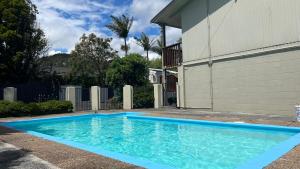 a blue swimming pool in front of a house at Aaron Court Motel Whangarei in Whangarei