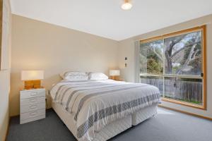 een slaapkamer met een bed en een groot raam bij Woolamai Waves Abode in Cape Woolamai