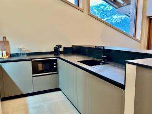 eine Küche mit einer schwarzen und weißen Arbeitsplatte in der Unterkunft Appartement neuf à Méribel, proche des pistes, balcon, service concierge inclus! - FR-1-613-103 in Les Allues + 15 Fotos