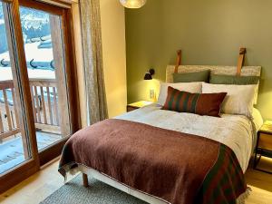 ein Schlafzimmer mit einem Bett und einem großen Fenster in der Unterkunft Appartement neuf à Méribel, proche des pistes, balcon, service concierge inclus! - FR-1-613-103 in Les Allues