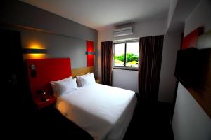 a hotel room with a white bed and a window at Hotel Africa in Maputo