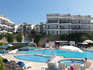 a swimming pool with chairs and umbrellas in front of a building at Sunset Beach Vip 1 Residences in Konaklı