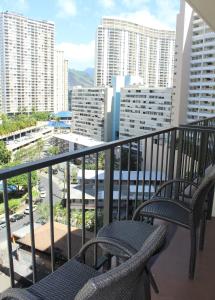 balkon z 2 krzesłami i widokiem na miasto w obiekcie Elevated Aqua Palms Waikiki Studio condo w mieście Honolulu