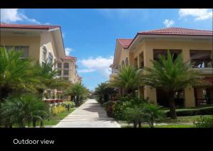 a walk way between two buildings with palm trees at San Remo Oasis Cebu- Vic Place in Cebu City