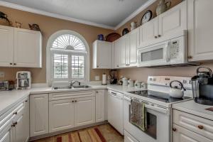 a white kitchen with white cabinets and a window at Luxury 2 Bedroom priced like a hotel., pets ok in Myrtle Beach