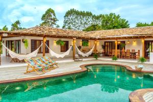 a house with a pool and a deck with hammocks at Casas Orixás em Trancoso in Trancoso