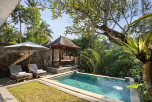 a pool with a gazebo next to a resort at Kawi Resort Ubud in Tegalalang