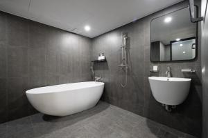 La salle de bains est pourvue d'une grande baignoire blanche et d'un lavabo. dans l'établissement Hotel Stay Inn, à Séoul