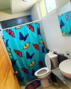 a bathroom with a blue shower curtain with butterflies at El Currican Juan Dolio in Juan Dolio