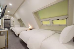 um quarto com 4 camas brancas e uma janela em Hotel Stay Inn em Seul