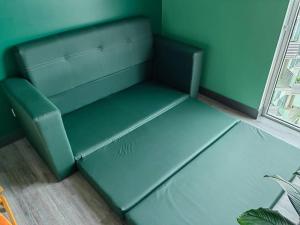 un divano verde seduto in una stanza accanto a una finestra di 1515 SECRT Sabana Hermoso Apartamento Totalmente Equipado a San José