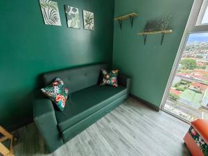 a green couch in a room with a window at 1515 SECRT Sabana Hermoso Apartamento Totalmente Equipado in San José