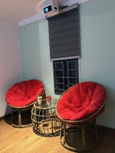 two chairs with red cushions sitting in front of a fireplace at Gachilly House - Your Cozy Home In The Heart Of The BMT City in Buon Ma Thuot
