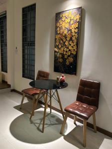 a table and two chairs and a painting on the wall at Gachilly House - Your Cozy Home In The Heart Of The BMT City in Buon Ma Thuot