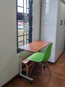 a desk and a green chair in front of a window at Gachilly House - Your Cozy Home In The Heart Of The BMT City in Buon Ma Thuot