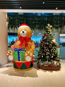 a large teddy bear sitting next to a christmas tree at Cheongpung Resort in Jecheon