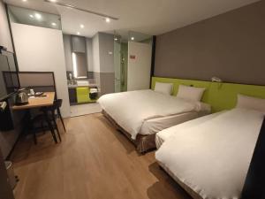 a hotel room with two beds and a table and a desk at Walker-Taoyuan in Taoyuan
