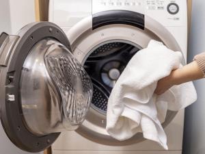 a person holding a towel in front of a washing machine at Tokyu Stay Nishi Shinjuku in Tokyo