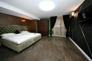 a bedroom with a large bed with a green headboard at FLY - Regim Hotelier Galati in Galaţi