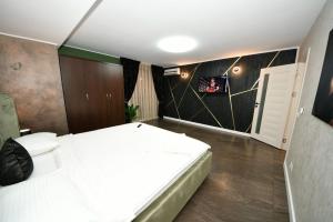 ガラツィにあるFLY - Regim Hotelier Galatiのベッドルーム1室(白いベッド1台、壁にテレビ付)