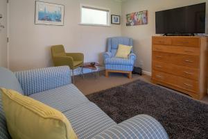 a living room with a couch and two chairs and a tv at Brougham Street B and B in Nelson
