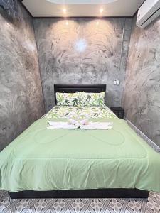 1 dormitorio con 1 cama con edredón verde en ชาลีรีสอร์ท ชุมพร, en Chumphon