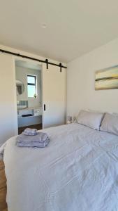 a large white bed in a room with a mirror at Beach Break Cabin 1 in Pohara