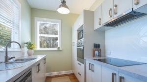 uma cozinha com armários brancos e um lavatório em Brook Nest em Nelson