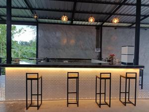 a kitchen with a bar with stools around it at ชาลีรีสอร์ท ชุมพร in Chumphon