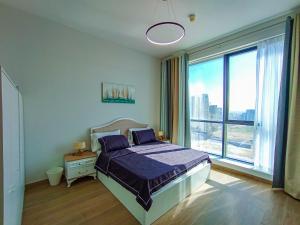 a bedroom with a bed and a large window at Luxury 1 Bedroom Flat with Dubai Coastline View in Sharjah