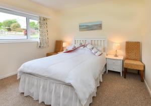 a bedroom with a white bed and a window at 10 Llwyn Onn Beach Hut in Abersoch