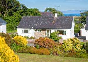 a white house with a garden in front of it at 10 Llwyn Onn Beach Hut in Abersoch