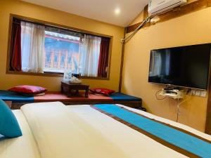 a room with a flat screen tv and a bed at Juxian Boutique Homestay in Lijiang