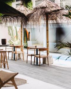 un patio con tavoli, sedie e ombrellone di paglia di Good Mantra Studio a Canggu