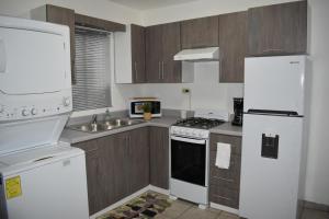 a kitchen with white appliances and wooden cabinets at Gabbys House in private neighborhood in Mexicali
