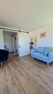 a living room with a blue couch and a door at Beach Break Cabin 2 in Pohara