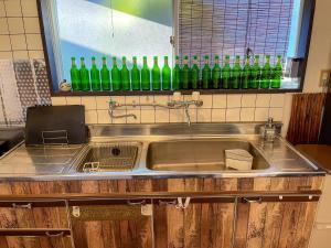 a kitchen sink with a bunch of green bottles on the wall at MtFuji Guest House Kikkake in Fujiyoshida +58 photos