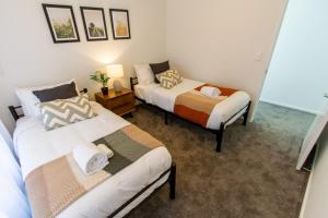 a bedroom with two beds and a table with a lamp at A touch of Luxury in Chch CBD in Christchurch