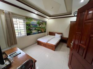 a small bedroom with a bed and a painting on the wall at Khách Sạn Hồng Hảo in Lao Cai