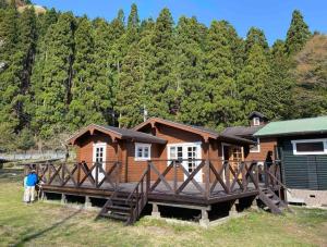 una cabaña de madera con porche y gente parada frente a ella en Log Cottage Yamanohiroba - Vacation STAY 40692v en Shiso