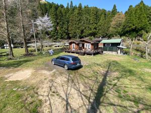 un coche aparcado en un patio frente a una casa en Log Cottage Yamanohiroba - Vacation STAY 40692v en Shiso