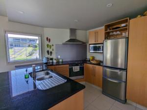 a kitchen with a sink and a stainless steel refrigerator at The Coastal Getaway in Mount Maunganui